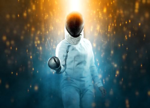 Fencer athlete wearing fencing costume holding the sword and mask. Isolated on black background with lights